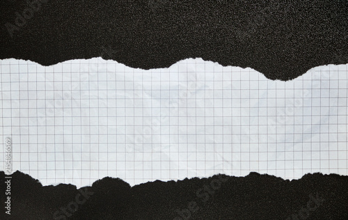 Centered torn strip of squared paper on a black background, rough edges, strong contrast, abstract template.