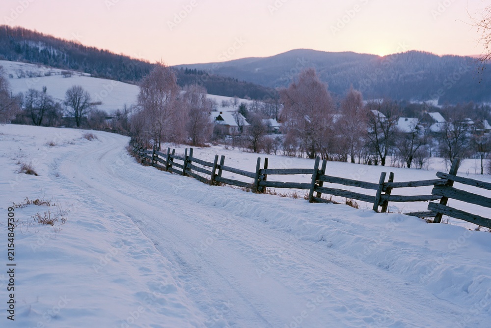 Obraz premium The Snowy Path Through A Quiet Countryside At Sunset With Rolling Hills