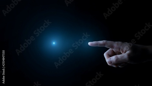 Hand pointing at a glowing blue light in darkness finger