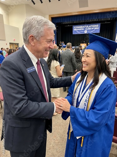 School administrator congratulating nursing graduate in blue gown