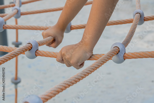 Quadro su tela Close up hands gripping outdoor rope climbing pyramid net structure on playgroun