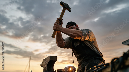 A silversmith works alone under a dramatic overcast sky at an outdoor forge, hammer raised above a small anvil in a solitary stance, the finished piece beside the workspace suggests a micro investme