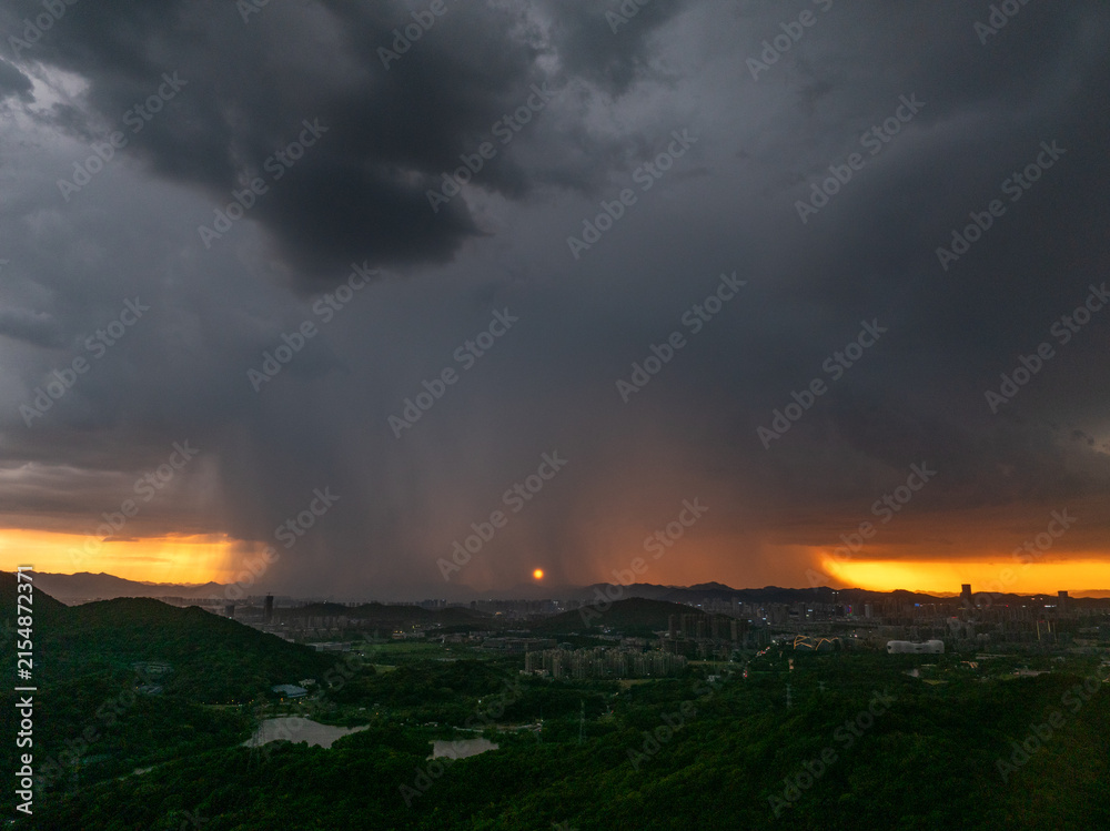 Fototapeta premium dark storm clouds gathering over city at sunset