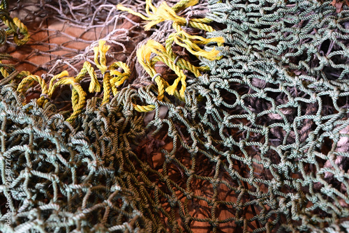 Close-up view of weathered fishing nets wrapped around round buoys, showing traditional commercial fishing equipment, rope, and maritime gear.