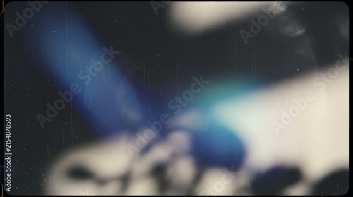 Abstract vintage film grain overlay with blue light leak and blurry dark background, creating a nostalgic and mysterious atmosphere.
