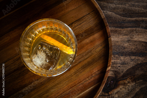 Close up of a classic old fashioned cocktail on a dark wooden background garnished with an orange twist.