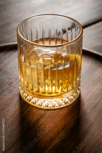 Close up of a classic old fashioned cocktail on a dark wooden background garnished with an orange twist.