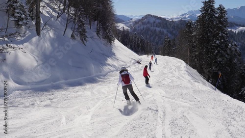Skiers and snowboarders skiing down prepared ski slope in scenic mountain landscape on sunny winter day. Showcasing winter sports and healthy, active lifestyle in alpine resort