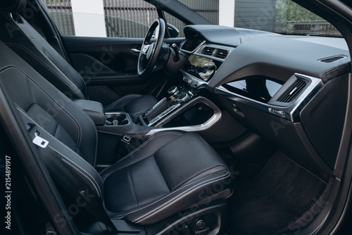 A modern car interior features black seats, a steering wheel, dashboard, center console, climate controls, and polished trim.