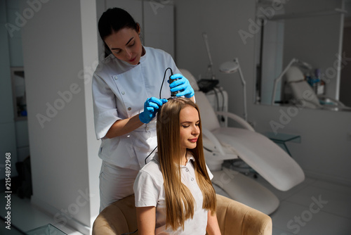 Detailed scalp examination by a dermatologist using a handheld trichoscope device helps identify early signs of alopecia.