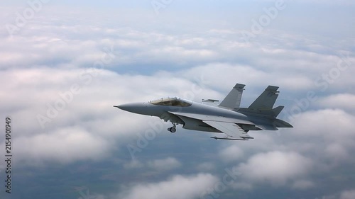 Military fighter jet flying above clouds in blue sky. Combat aircraft in aerial flight.