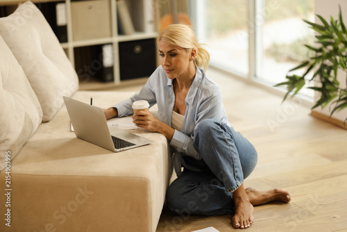 Woman Working on Laptop in Office Space With Coffee Cup in Hand