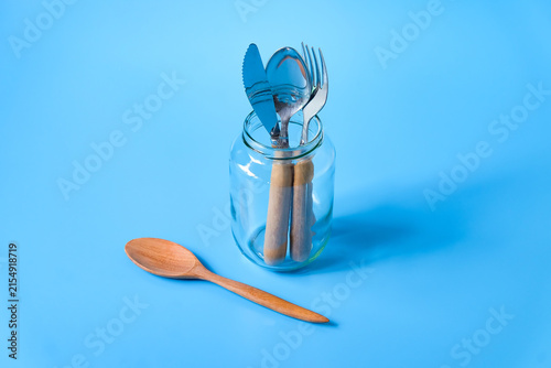 Knife, spoon and fork in the glass bottle on background.