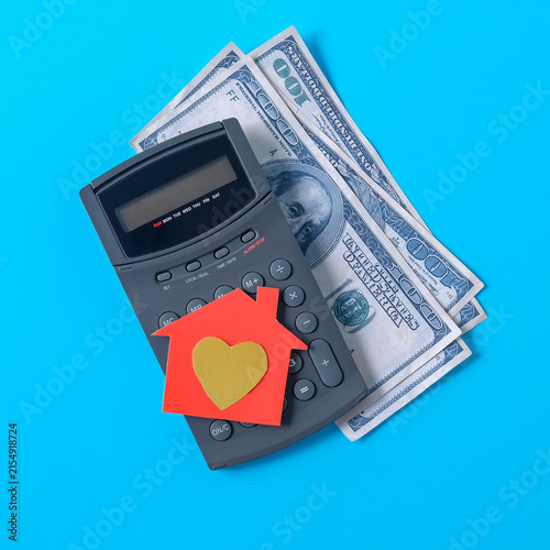 A paper house with golden heart symbol on calculate.