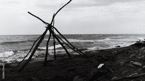 A black and white  of a teepee on the beach, great for travel or outdoor lifestyle scenes
