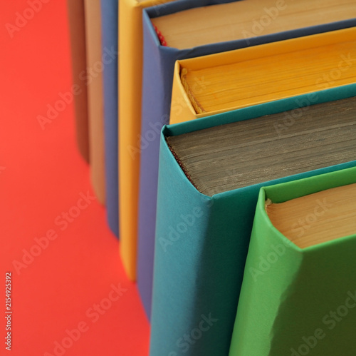 Books with colorful paper covers are lined up against colorful paper backgrounds. School education featuring attractive, bright, and colorful books.