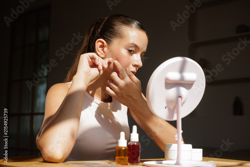 Young woman applying acne patch during daily facial skin care