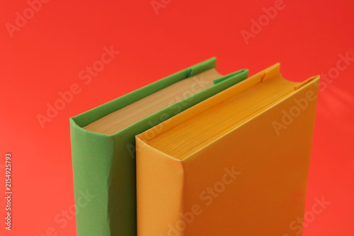 Books with colorful paper covers are lined up against colorful paper backgrounds. School education featuring attractive, bright, and colorful books.