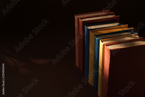 Books with colorful paper covers are lined up against colorful paper backgrounds. School education featuring attractive, bright, and colorful books.