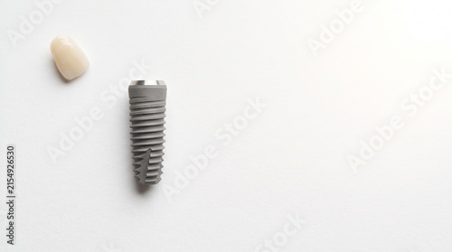 Dental implant and prosthetic tooth on a light background  