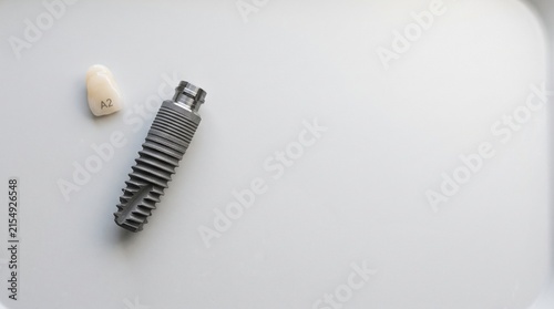 Dental implant and prosthetic tooth on a neutral background  