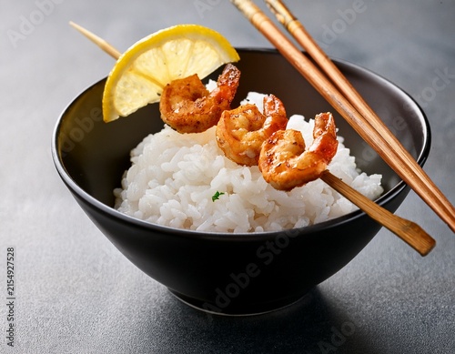 rice bowl with chopsticks shrimp skewer and lemon slice