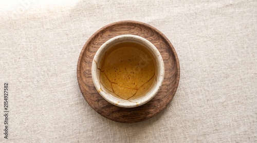 Tea in a rustic cup on a wooden coaster against a textured background  