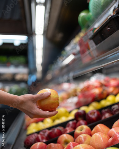 A person’s hand picking a red apple