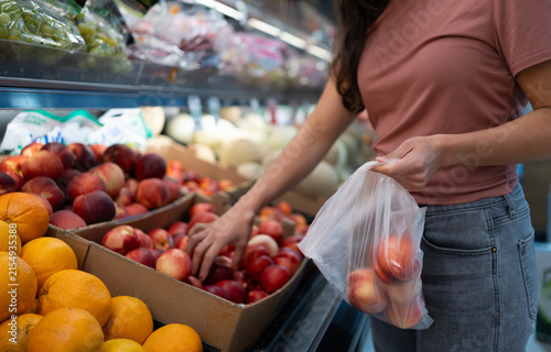 A woman sorting fruit to put it into a bag.