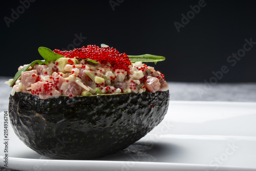 Fresh salad with fish, caviar, and avocado on a plate.