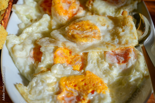 Batch of fried eggs with golden, slightly set yolks and crispy edges. Freshly cooked fried eggs in a pan with golden runny yolks.