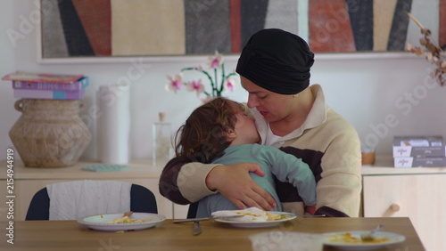 Canvastavla Mother comforting crying toddler at dining table in family home during cancer re