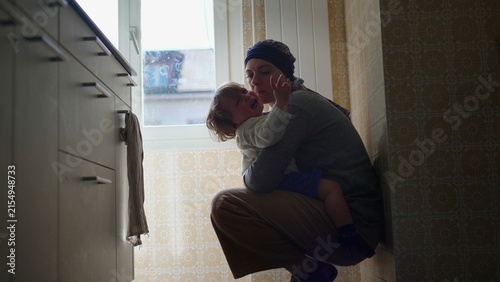 Fotografía Mother comforting upset toddler with affectionate embrace on kitchen floor, nurt