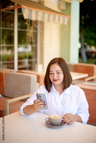 smiling businesswoman texting on mobile phone at coffee break on terrace