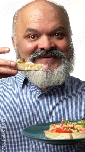 Indian Asian senior gentleman with a white beard, enjoying a slice of pizza during snack time expressing happiness