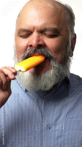 Indian Asian senior businessman with a white beard, holding a candy ice cream cone, feeling sudden toothache shows discomfort on face
