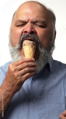 Indian Asian senior businessman with white beard savoring a chocolate ice cream cone, enjoying a casual moment  of joy and relaxation