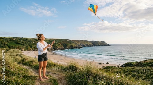 Woman flying a colorful kite on a cliff overlooking a scenic beach and ocean