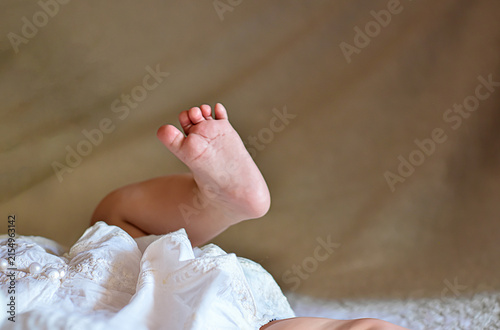 Obraz na plátně Close-up of a tiny baby foot raised in the air while lying on a soft blanket