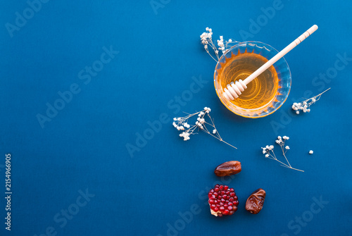 Фотография Rosh Hashanah Jewish New Year celebration with honey, wooden honey dipper, pomeg