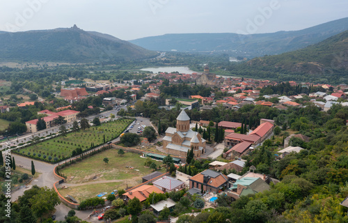 Panoramic view of a historic church, residential area, and mountainous landscape in Georgia