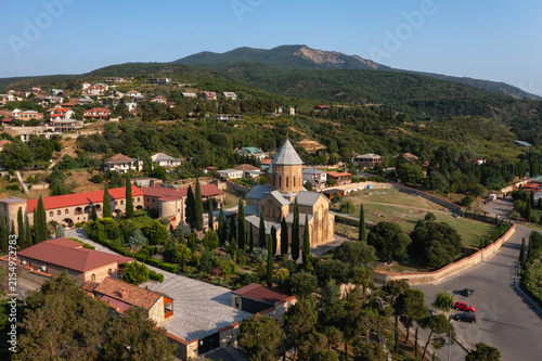 Historic Orthodox church complex surrounded by green hills and Caucasus mountains