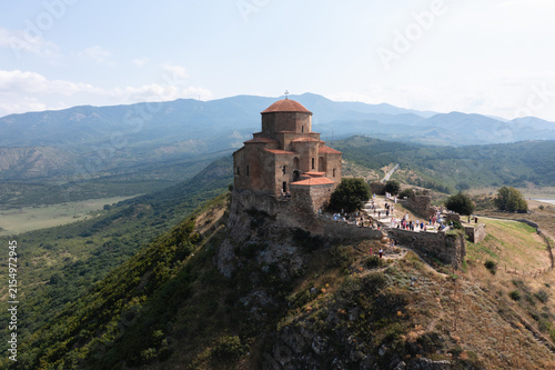 Ancient stone church standing on a rocky promontory above a picturesque mountainous valley