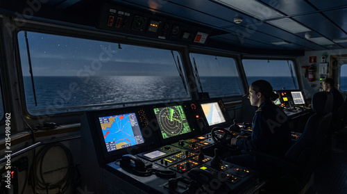 Bridge of Command: A dedicated crew navigates the open sea under the watchful eye of the moon, illuminated by the glow of advanced navigation systems, a testament to maritime precision and teamwork.
