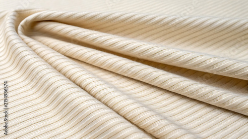 Close-up of smooth light beige fabric texture with soft folds for elegant home decor and fashion design