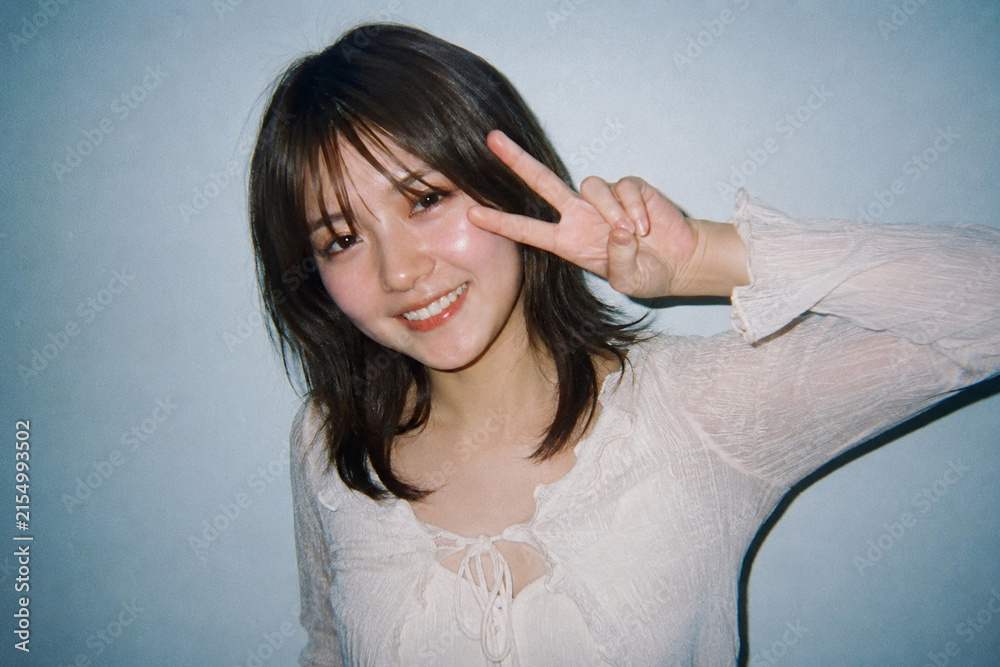 Fototapeta premium 白いブラウスでピースサインをする女性