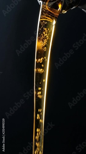 Golden engine oil pouring down against a dark background