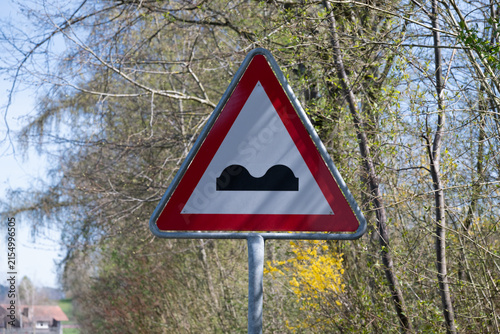 Caution Potholes. The Caution! Potholes traffic sign is a clear warning signal that alerts drivers to potential hazards on the road. It consists of a red triangle on a white background