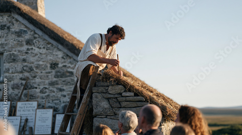 A roof thatcher working alone in a desolate moorland setting, a nuclear family watching from below as heritage food preservation techniques are explained through hand lettered