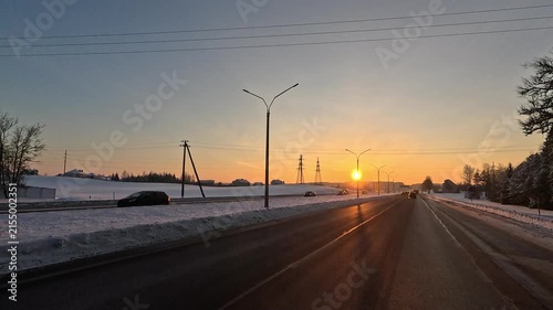 Winter frosty snowy sunset, orange landscape and road.